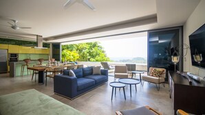 Ein modernes Wohnzimmer mit einem blauen Sofa, einem Essbereich und einer Küche im Hintergrund.
