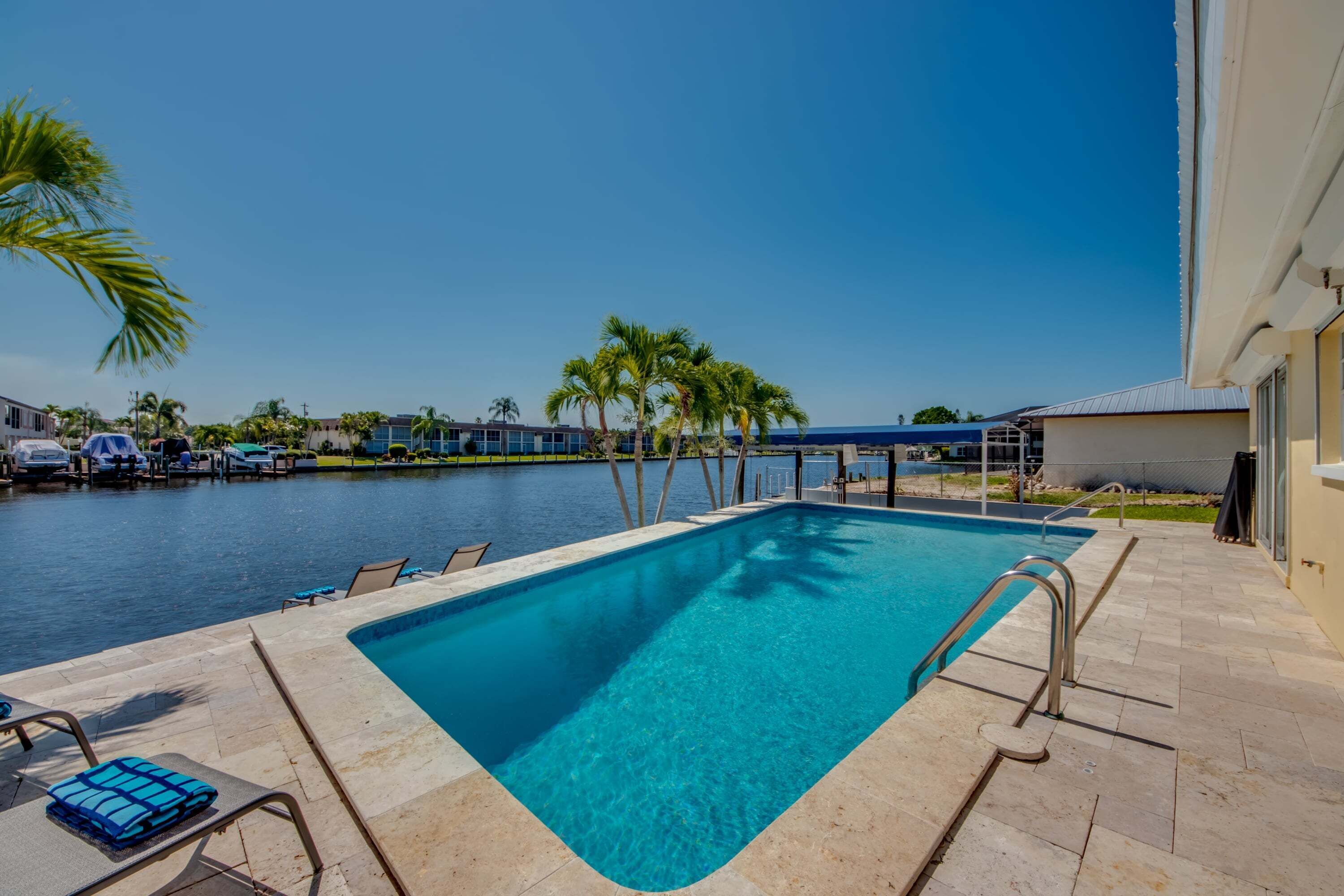 A swimming pool with lounge chairs and a view of the water.