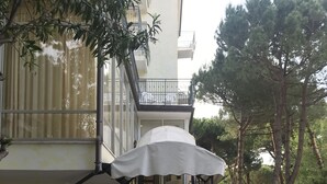A stone-paved entrance to a building with a staircase, potted plants, and a car parked nearby. - Hotel Augustus Milano Marittima (Cervia)