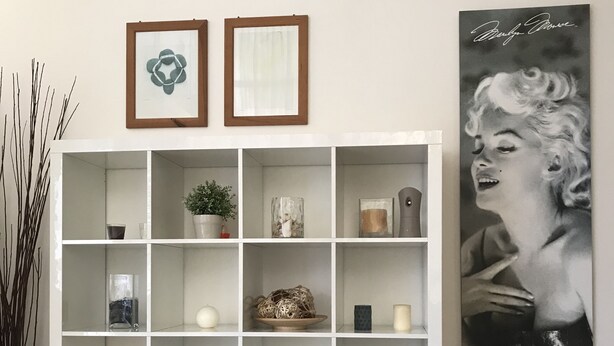 A white shelving unit with various decorative items, a framed picture, and a large poster on the wall. - Hotel Augustus Milano Marittima (Cervia)