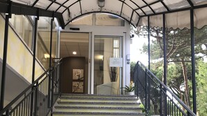 A staircase with a metal railing leading to a covered entrance. - Hotel Augustus Milano Marittima (Cervia)