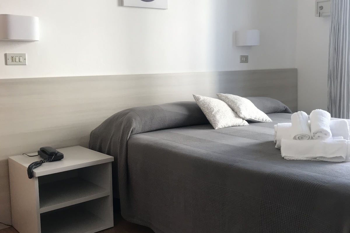 A neatly arranged hotel room with a bed, bedside tables, and a wall-mounted picture.