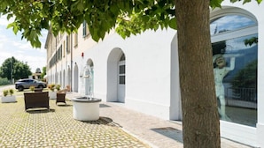 A building with a paved walkway, a fountain, and a tree. - Bluelake Inn - Ostello (Olginate)