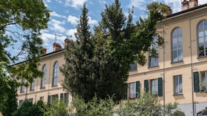 A multi-story building with arched windows and a central tree. - Bluelake Inn - Ostello (Olginate)