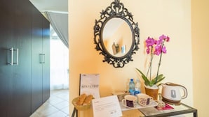 A hotel reception area with a mirror, a bowl of pastries, a coffee maker, and a vase of flowers. - Bluelake Inn - Ostello (Olginate)