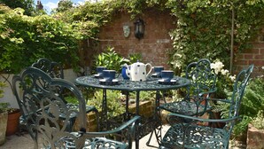 A round metal table with chairs, a teapot, and blue cups. - Crown Cottage (Rye)