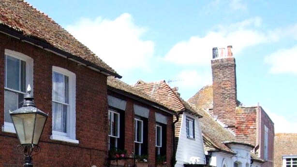 A traditional brick building with a shop entrance, a visible sign for a museum, and a street lamp. - Crown Cottage (Rye)