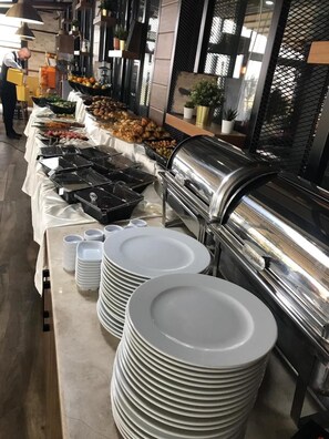Un buffet proposant une variété de plats et des assiettes blanches empilées.
