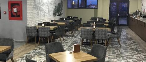 A restaurant with multiple tables and chairs, a patterned floor, and a mural on the wall.