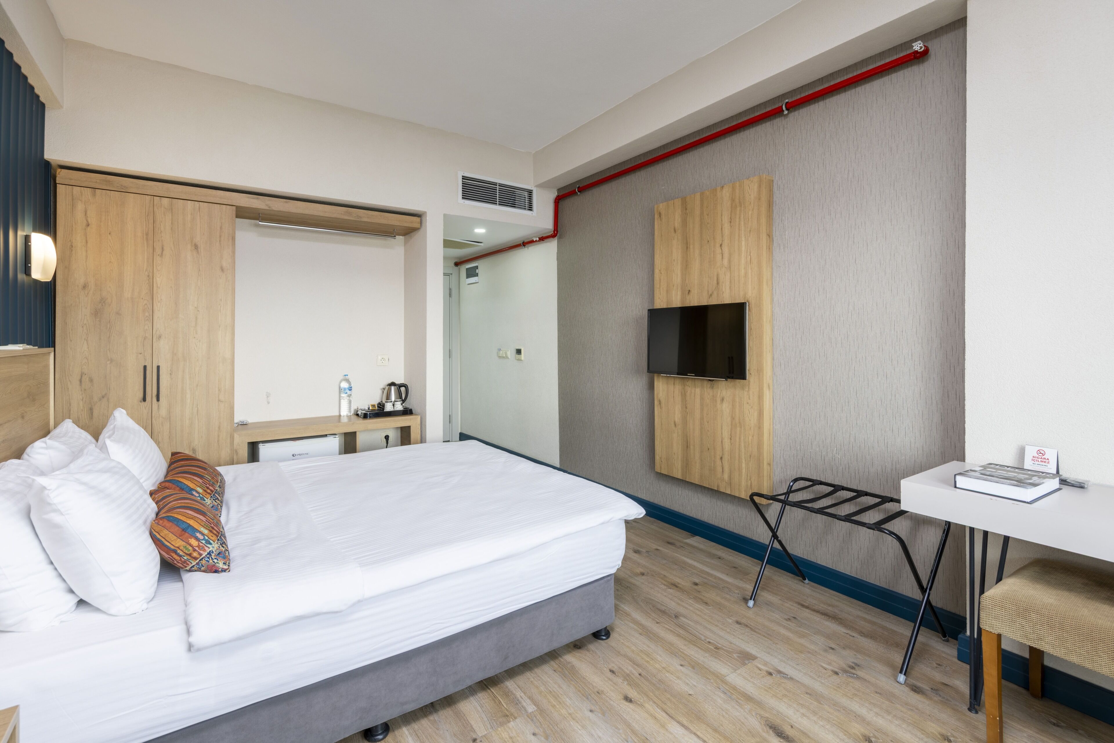 A hotel room with a bed, a desk, a TV, and a wardrobe.