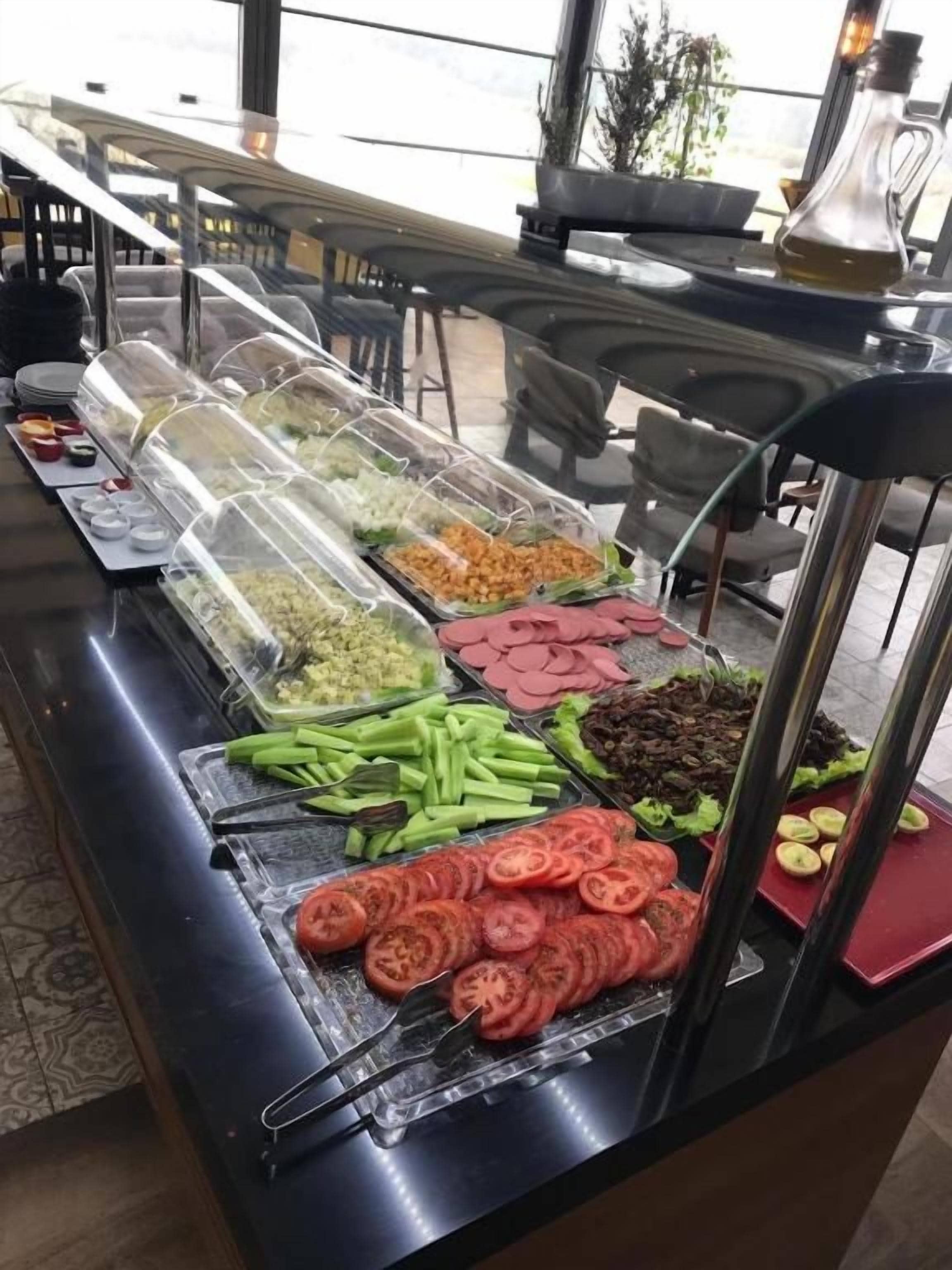 A buffet with various food items including sliced tomatoes, green beans, and other vegetables.