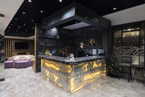 Un espace d’accueil avec un comptoir en marbre, une horloge et un sapin de Noël.
