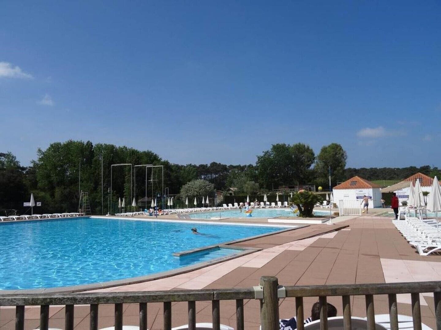 Une piscine dotée d’une terrasse carrelée, de chaises longues et d’un poste de surveillance pour les sauveteurs.
