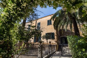 A building with a stone facade, green shutters, and a gated entrance. - King Arthur's Houses (Agrigento)