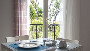 Une table à manger dressée avec des assiettes, des bols et une tasse, donnant sur un paysage verdoyant.