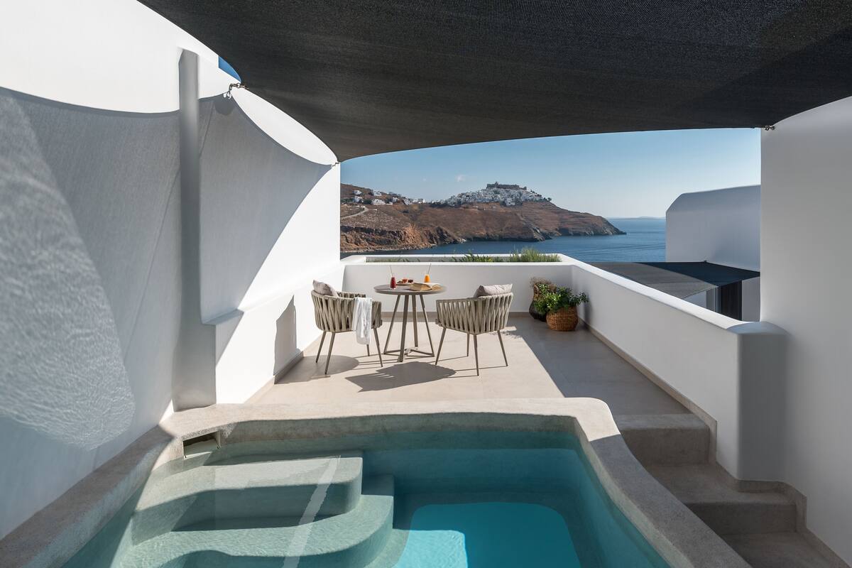 Un espace piscine extérieur moderne offrant une vue sur la mer et une île au loin.
