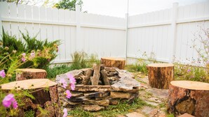 Un hogar de piedra rodeado de taburetes de madera y una cerca blanca de piquete.