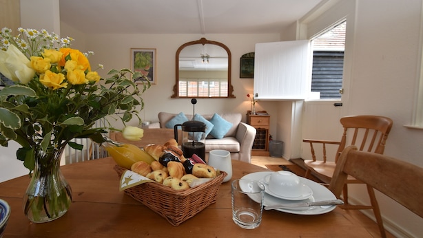 A dining table with a basket of bread, a vase of flowers, and a glass of water.