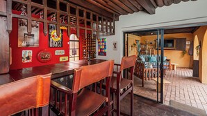 A bar area with wooden chairs and a red counter, featuring various memorabilia and a glass display case. - Airport Tower Lodge (Kempton Park)