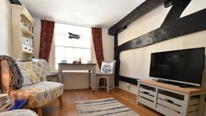 A cozy living room with a television, a patterned sofa, a small table, and a bookshelf. - Old Town Bolthole (Hastings)