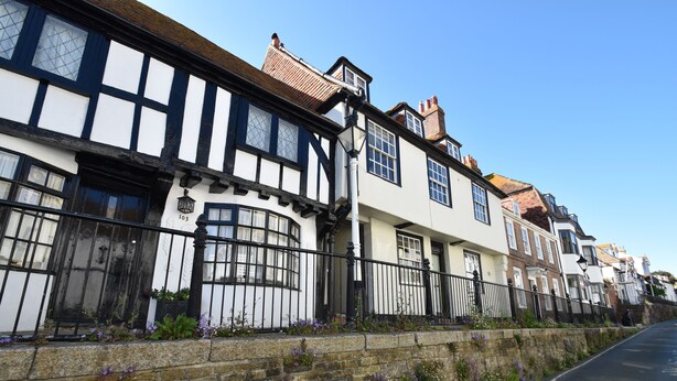 A row of traditional half-timbered houses with stone walls and a paved street. - Old Town Bolthole (Hastings)