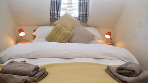 A neatly made bed with white linens, two pillows, and a yellow blanket. - Old Town Bolthole (Hastings)