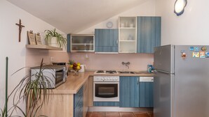 Eine kleine Küche mit integriertem Backofen, einer Mikrowelle, einem Spülbecken und einem Kühlschrank.