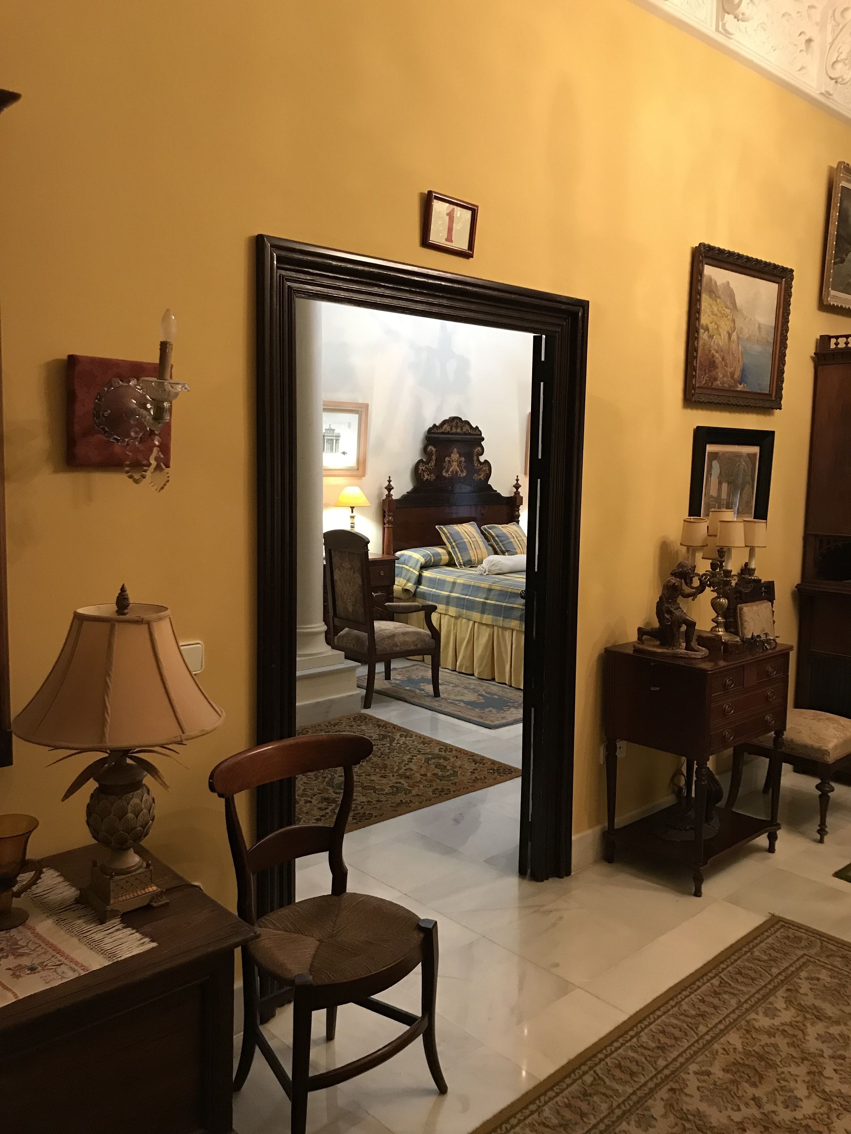 A room with a bed, a chair, a lamp, and a dresser.