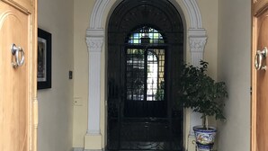 A grand entrance with a black door, a decorative arched doorway, and a chandelier. - Casa San José (Palma del Rio)