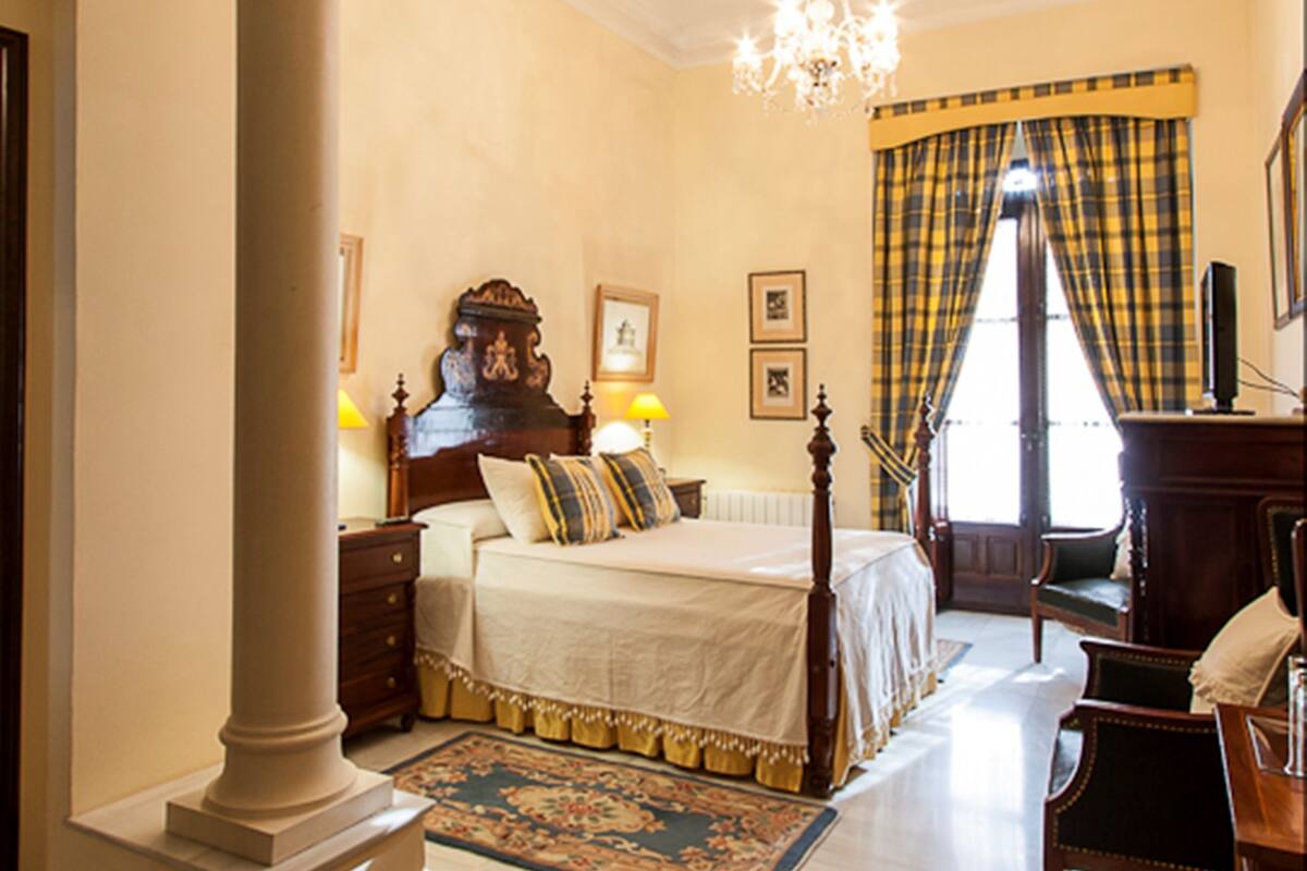 Une chambre à coucher avec un grand lit, un lustre, un bureau et une chaise.