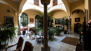 An interior with a high ceiling, arched columns, and multiple potted plants. - Casa San José (Palma del Rio)