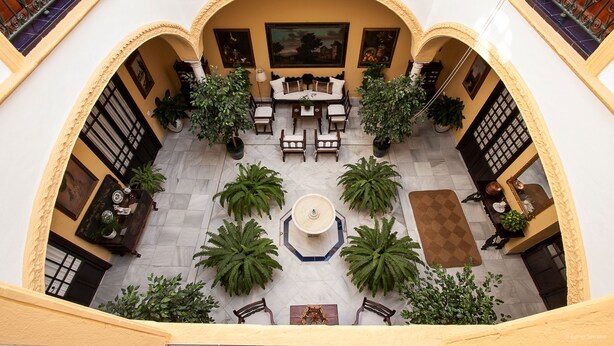 A courtyard with a central seating area, potted plants, and a fountain. - Casa San José (Palma del Rio)