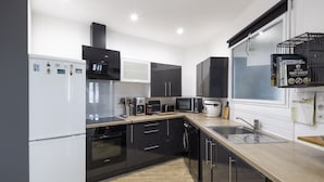 A modern kitchen with black and white appliances, a wooden countertop, and a window with a black shelf.
