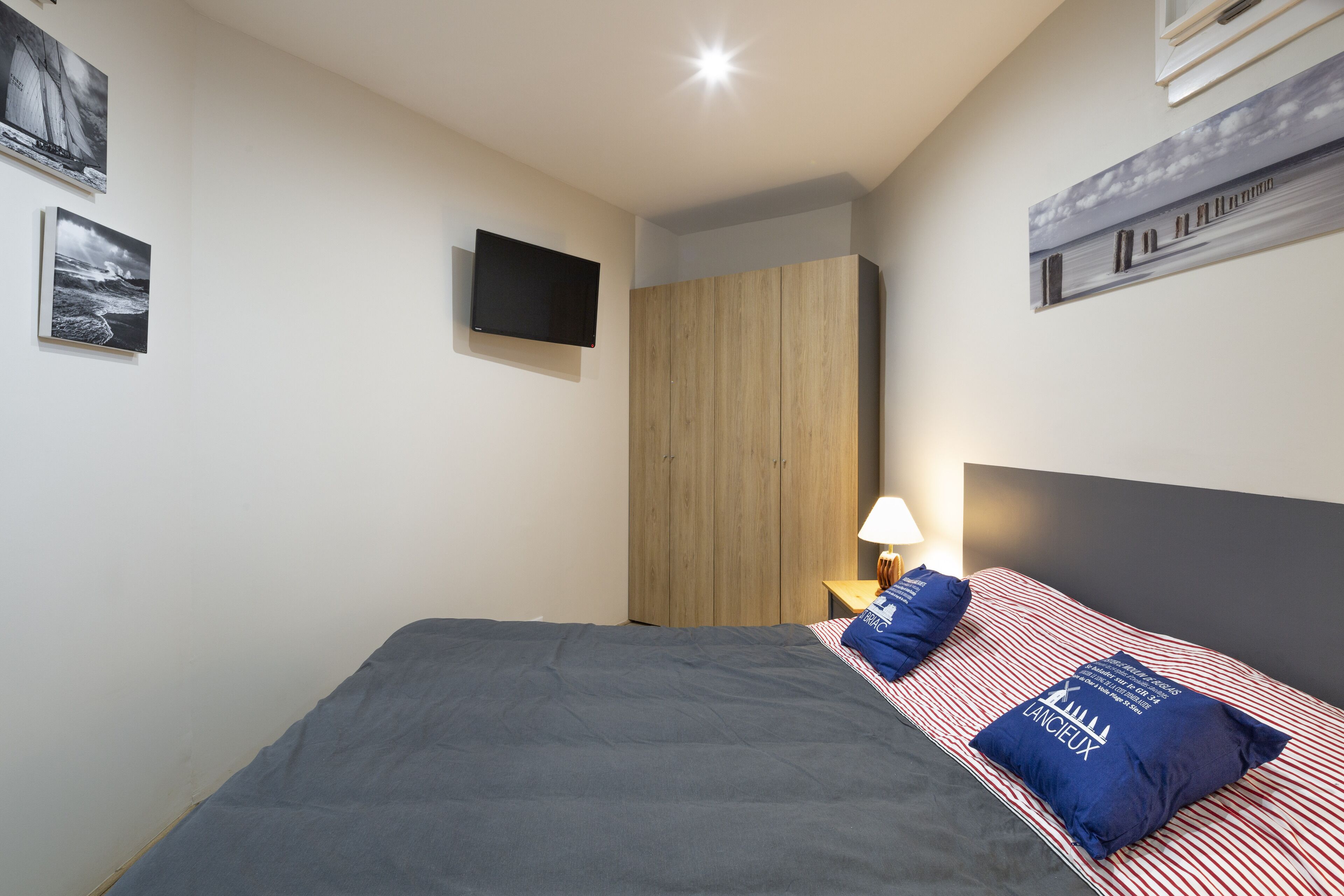 A bedroom with a bed, a TV mounted on the wall, and artwork on the walls.