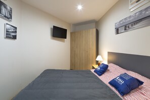 Ein Schlafzimmer mit einem Bett, einem an der Wand befestigten Fernseher und Kunstwerken an den Wänden.