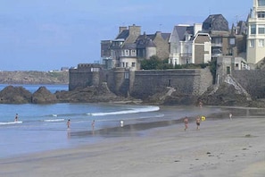 A beach with people, a stone wall, and buildings in the background. - Very nice apartment in Paramé (Saint-Malo)