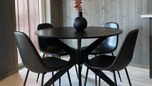 A dining area with a round table, four chairs, and a vase with dried flowers. - Fagernes Camping (Nord-Aurdal)