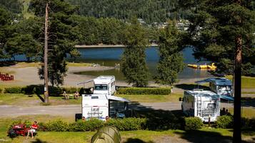 Ein Campingplatz mit Wohnmobilen, einem Zelt und Blick auf einen See.