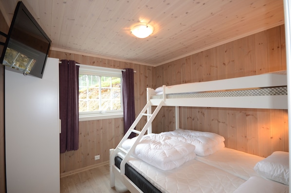 Habitación con literas, paredes de madera, una ventana con cortinas y una lámpara en el techo.