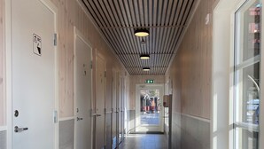 A corridor with wooden panel walls, white doors, and a tiled floor. - Fagernes Camping (Nord-Aurdal)