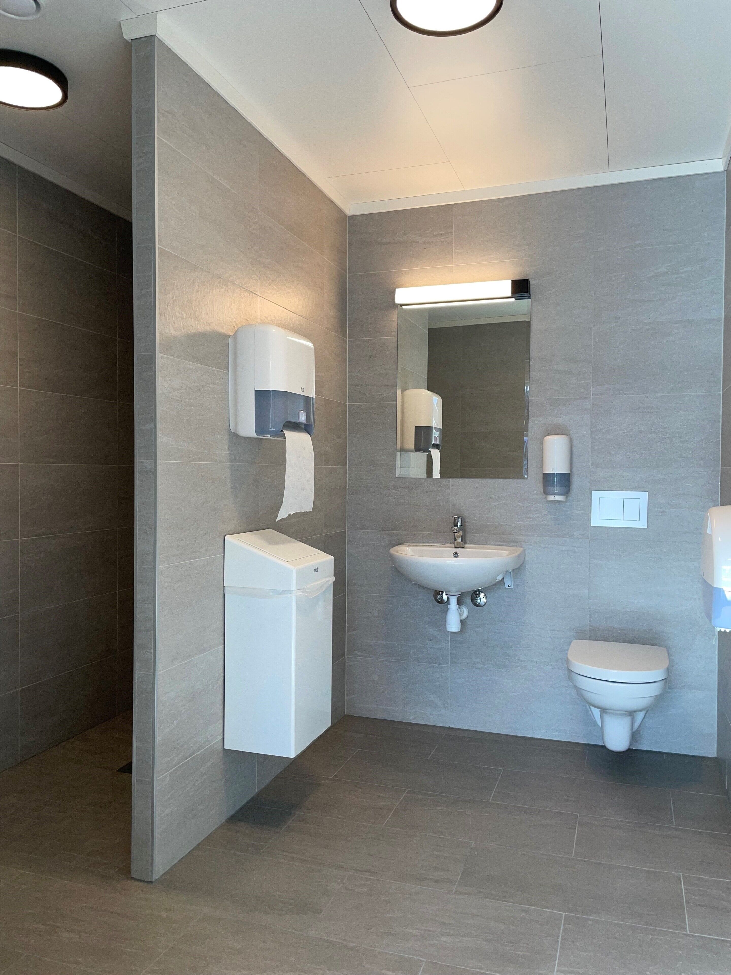 Un baño moderno con inodoro, lavamanos y secador de manos.