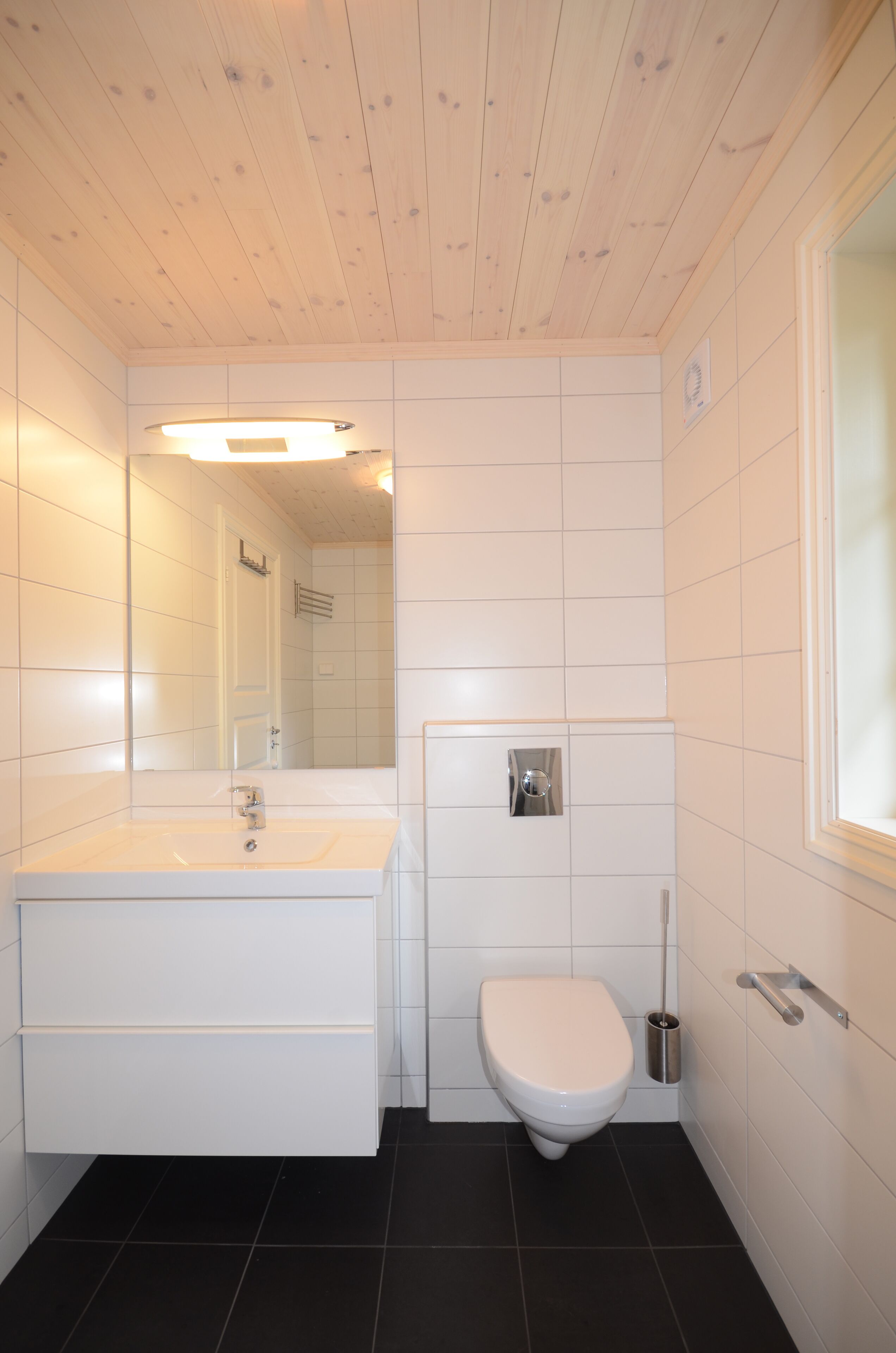 A bathroom with a white sink, a toilet, and a mirror.