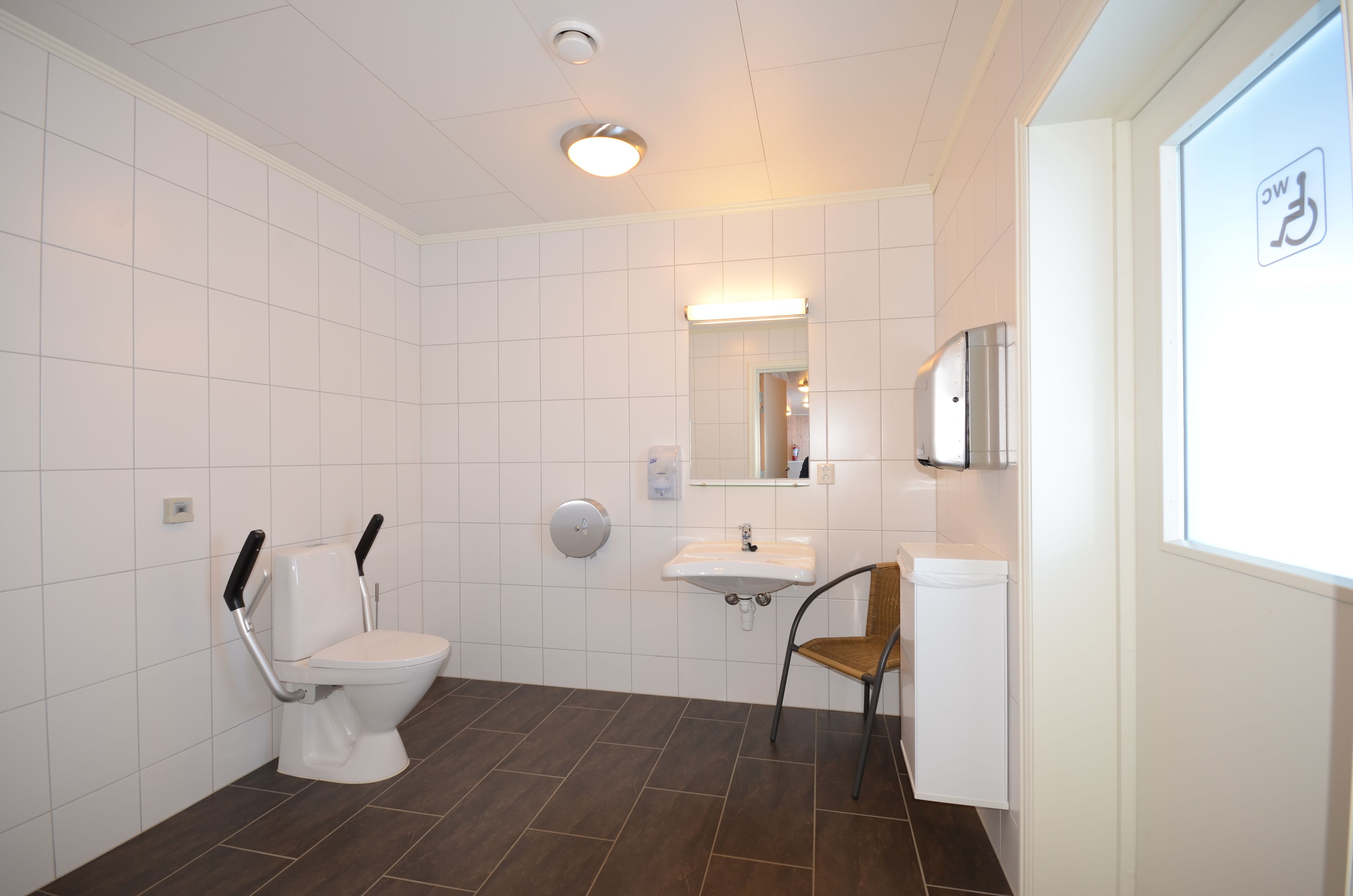 A modern bathroom with a toilet, sink, and chair.
