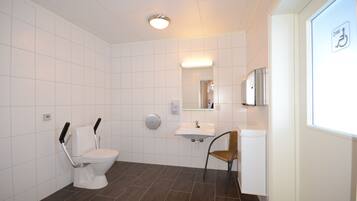 A modern bathroom with a toilet, sink, and chair.