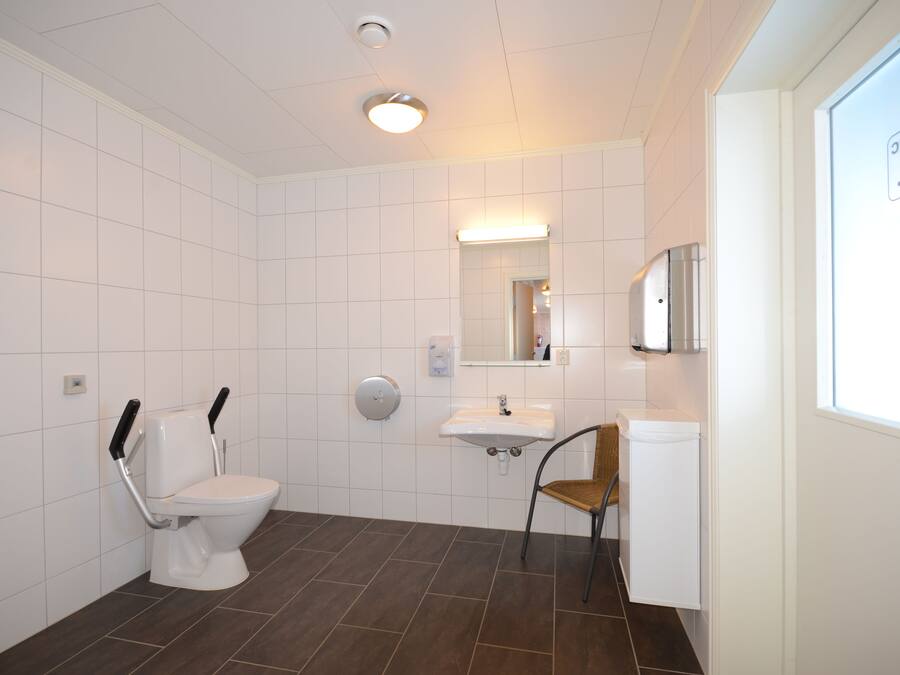 A modern bathroom with a toilet, sink, and chair.