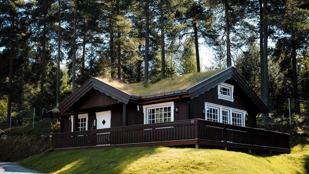 A cabin with a wooden deck, large windows, and a sloped roof. - Fagernes Camping (Nord-Aurdal)