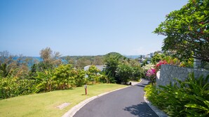 A curved road with lush greenery and a stone wall on one side. - Beautiful 3-Bedroom Villa at Surin Beach (Choeng Thale)