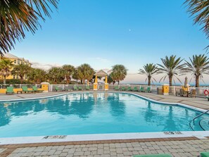 A swimming pool with a clear blue water, surrounded by palm trees and a white fence. - 303W ~ Captivating 3BR/3BA condo with a Gulf view (Gulf Shores)