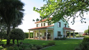 A two-story house with a covered porch and a well-maintained lawn. - Casa da Agra, villa with pool and splendid garden (A Coruña)