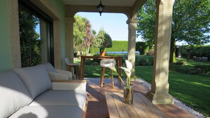 A covered patio with a sofa, chairs, and a table. - Casa da Agra, villa with pool and splendid garden (A Coruña)